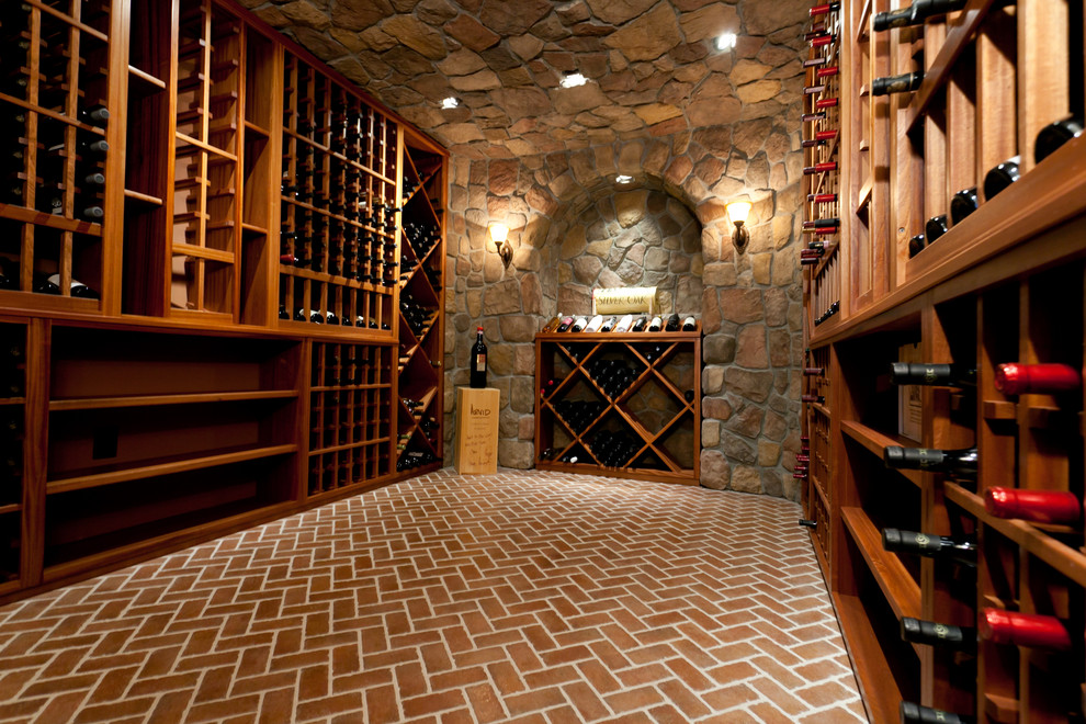 Aménagement d'une grande cave à vin classique avec un sol en brique, des casiers et un sol rouge.