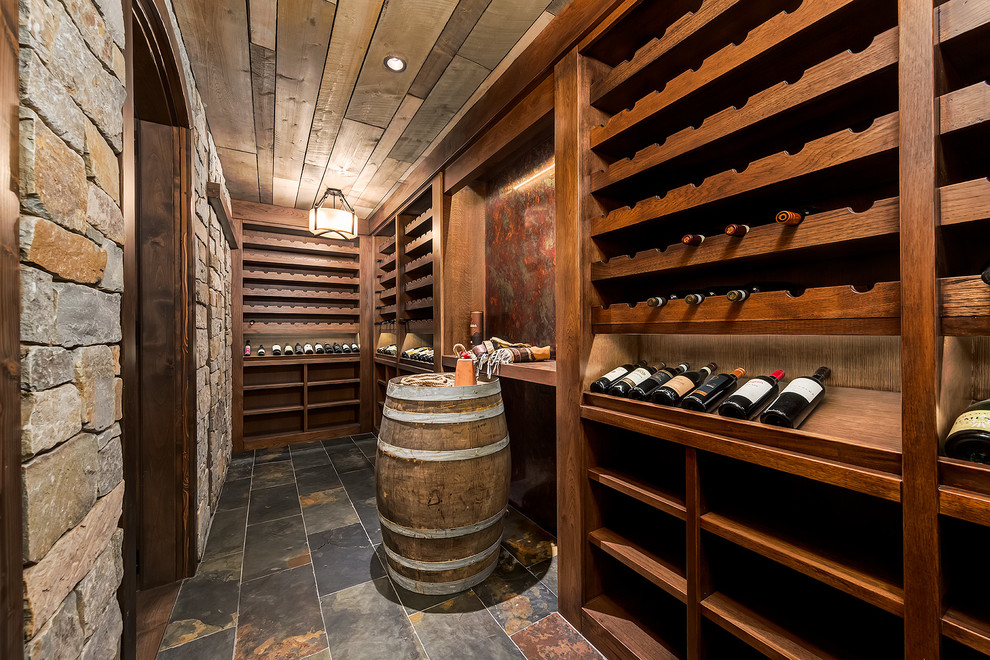 Cette image montre une cave à vin craftsman de taille moyenne avec un sol en ardoise et un présentoir.