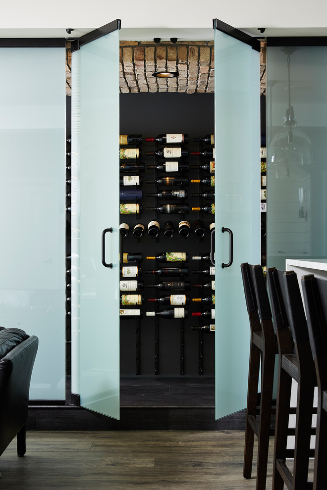 Expansive modern wine cellar in Minneapolis with vinyl flooring, display racks and black floors.
