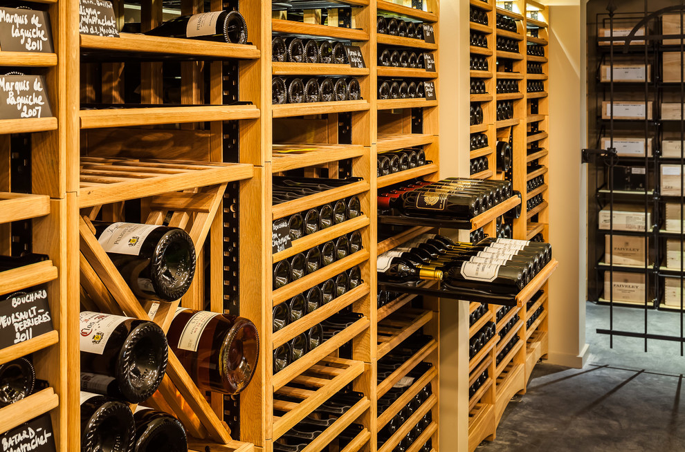 Example of a large mountain style concrete floor wine cellar design in Surrey with storage racks