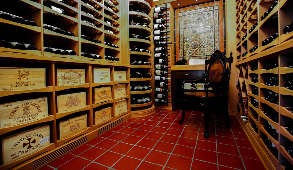 Cette photo montre une grande cave à vin chic avec tomettes au sol et un présentoir.