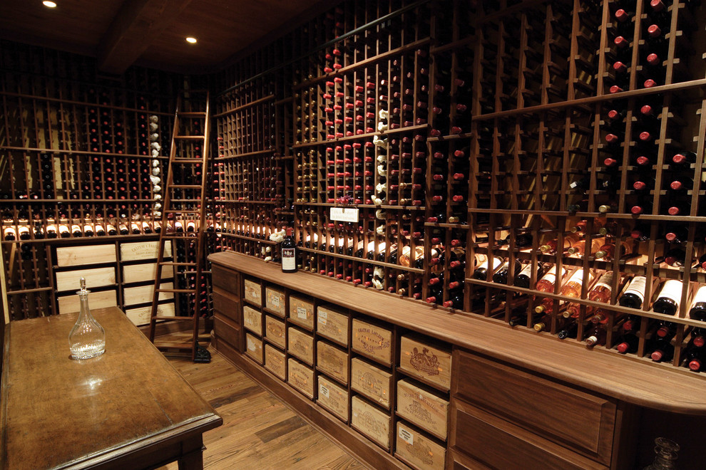 Large elegant medium tone wood floor and beige floor wine cellar photo in Phoenix with storage racks