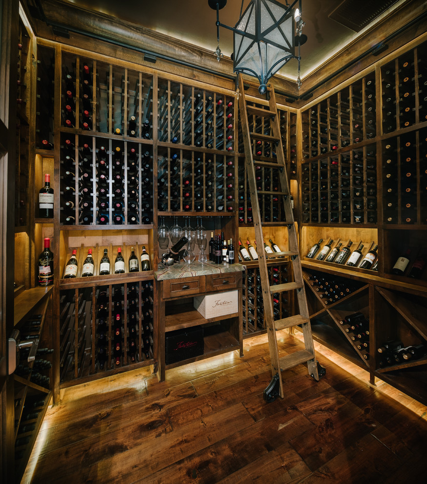 Cette image montre une cave à vin traditionnelle de taille moyenne avec parquet foncé et des casiers.