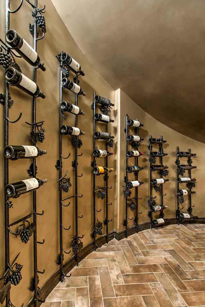Design ideas for a mediterranean wine cellar in Omaha with porcelain flooring, display racks and brown floors.