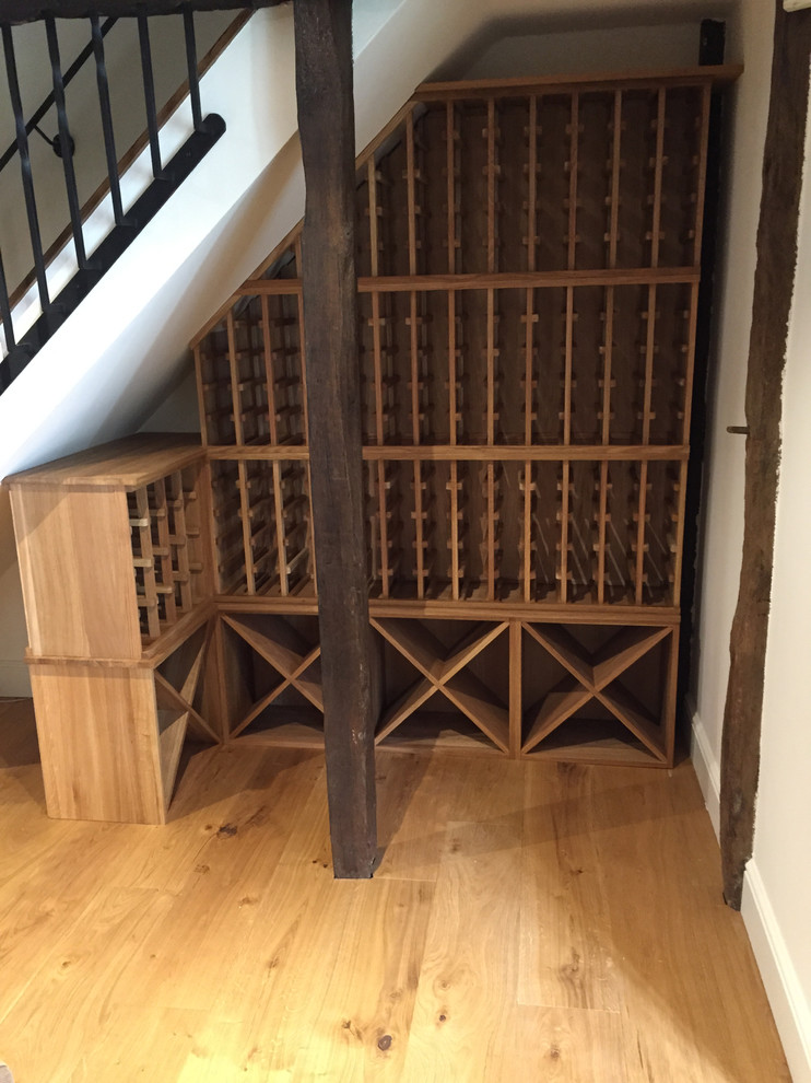 Bild på en liten funkis vinkällare, med vinhyllor, ljust trägolv och brunt golv