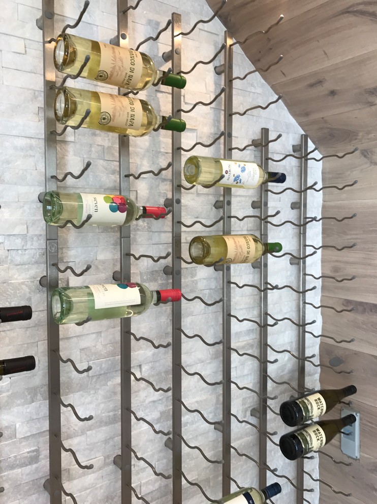 Exempel på en mellanstor klassisk vinkällare, med ljust trägolv och vinhyllor