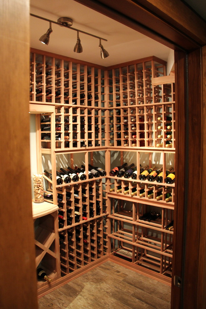 Wine cellar - mid-sized rustic medium tone wood floor and brown floor wine cellar idea in Other with storage racks
