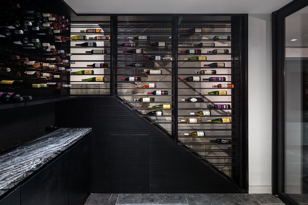 Large modern wine cellar in New York with limestone flooring, display racks and black floors.
