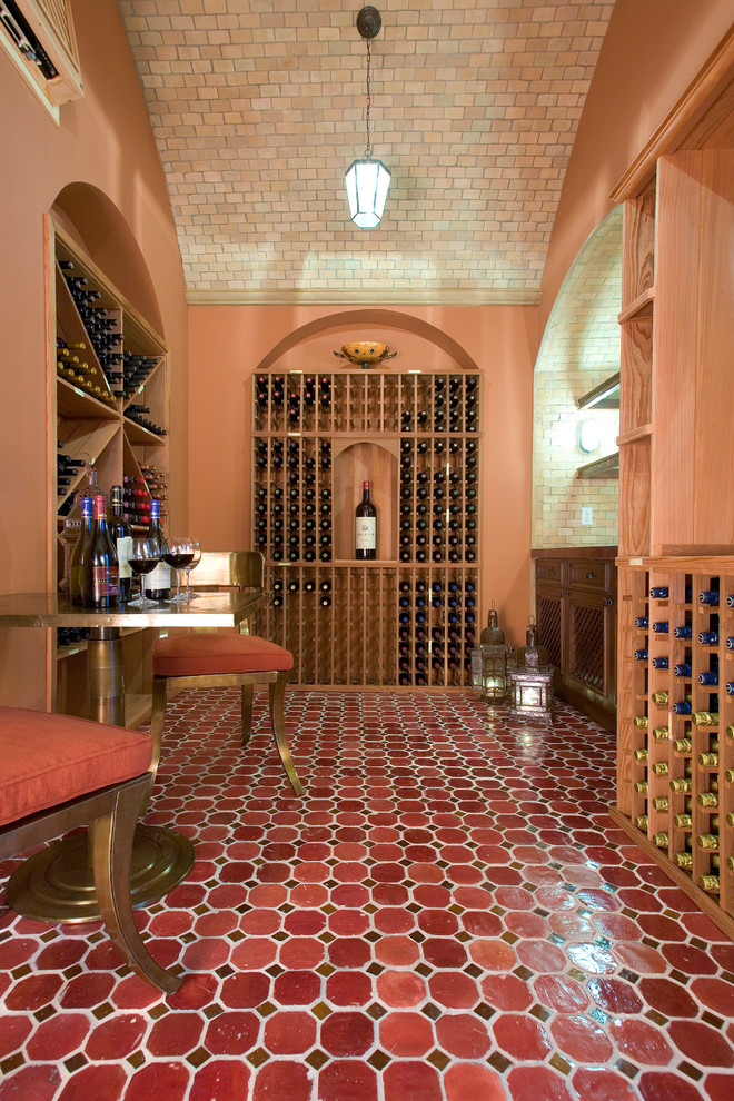 Стильный дизайн: винный погреб в средиземноморском стиле с стеллажами и красным полом - последний тренд