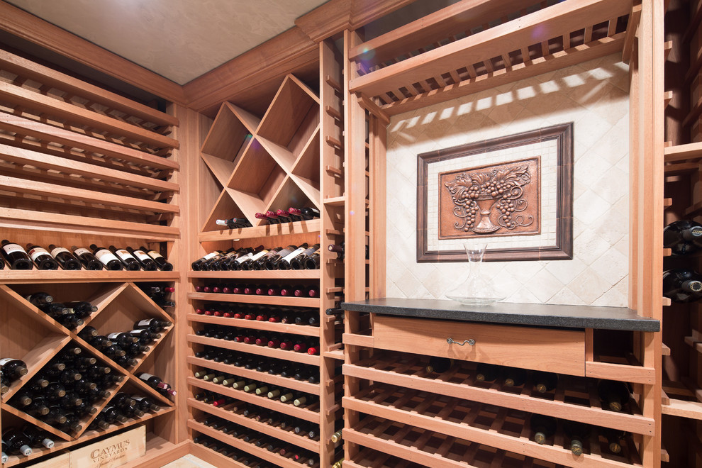 Idée de décoration pour une grande cave à vin tradition avec des casiers et un sol en travertin.