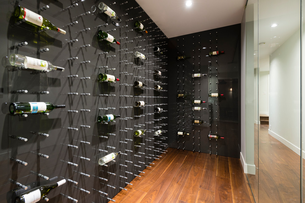 Idée de décoration pour une cave à vin design de taille moyenne avec un sol en contreplaqué et des casiers.