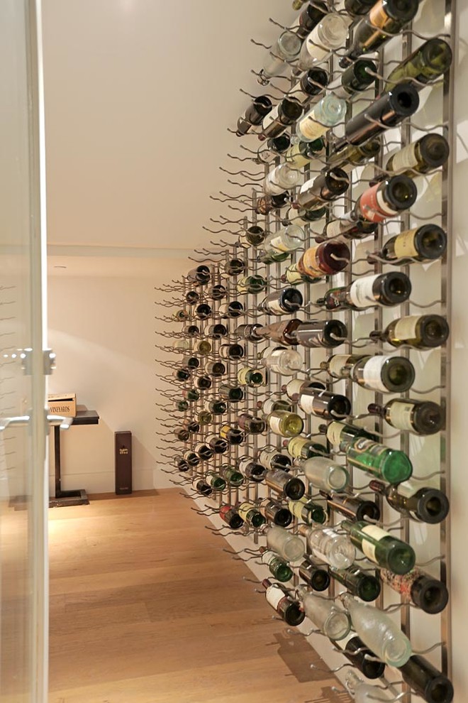 This is an example of a medium sized modern wine cellar in Los Angeles with medium hardwood flooring and display racks.