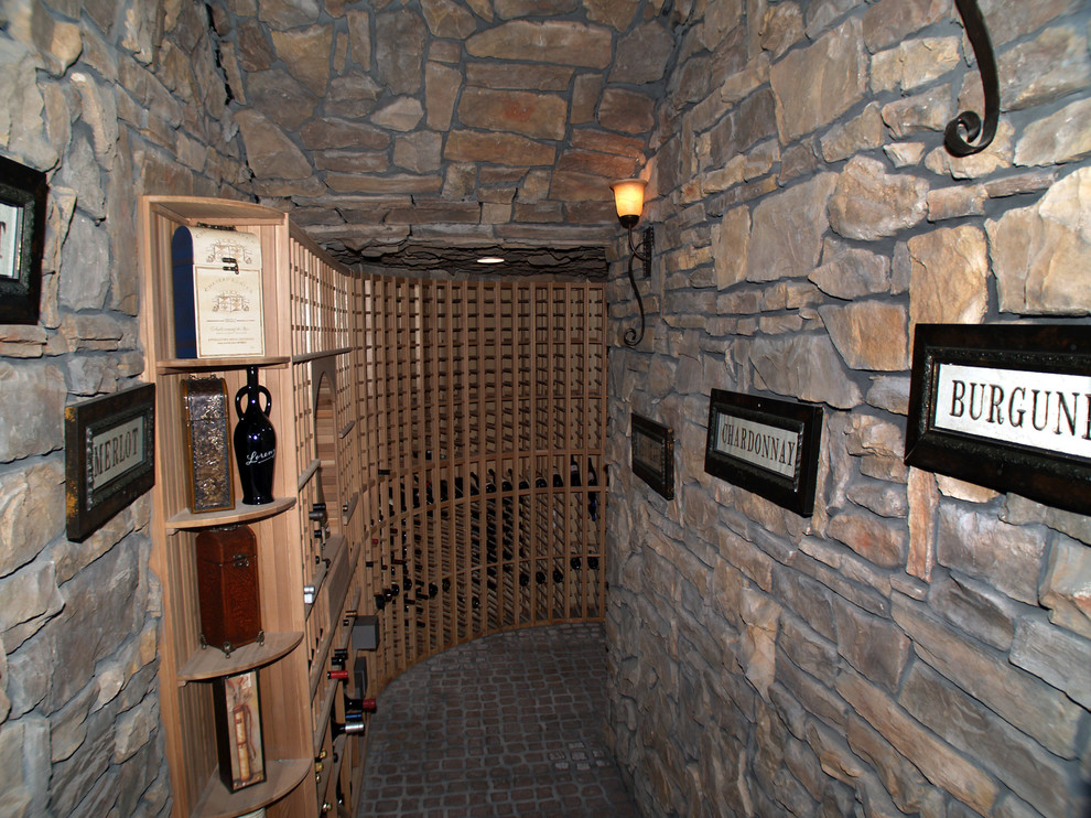 Example of a huge tuscan brick floor and beige floor wine cellar design in Las Vegas with storage racks