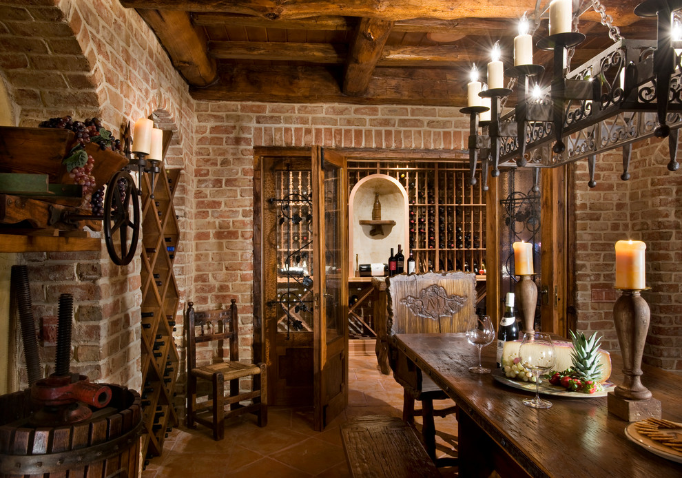 Klassisk inredning av en mycket stor vinkällare, med klinkergolv i terrakotta, vinställ med diagonal vinförvaring och beiget golv