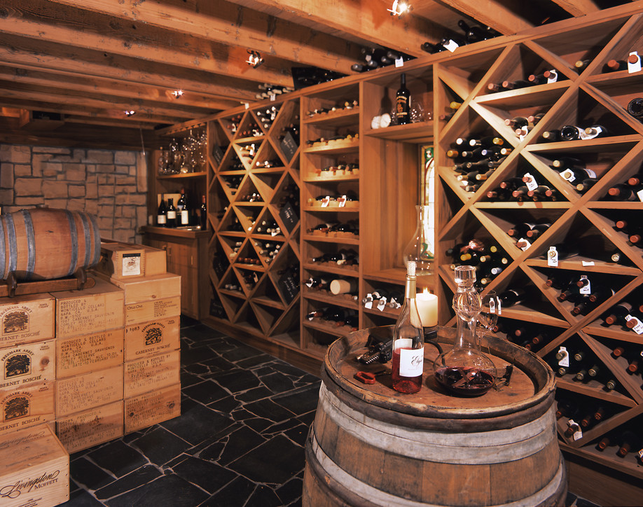 Medium sized rustic wine cellar in San Diego with ceramic flooring, cube storage and black floors.