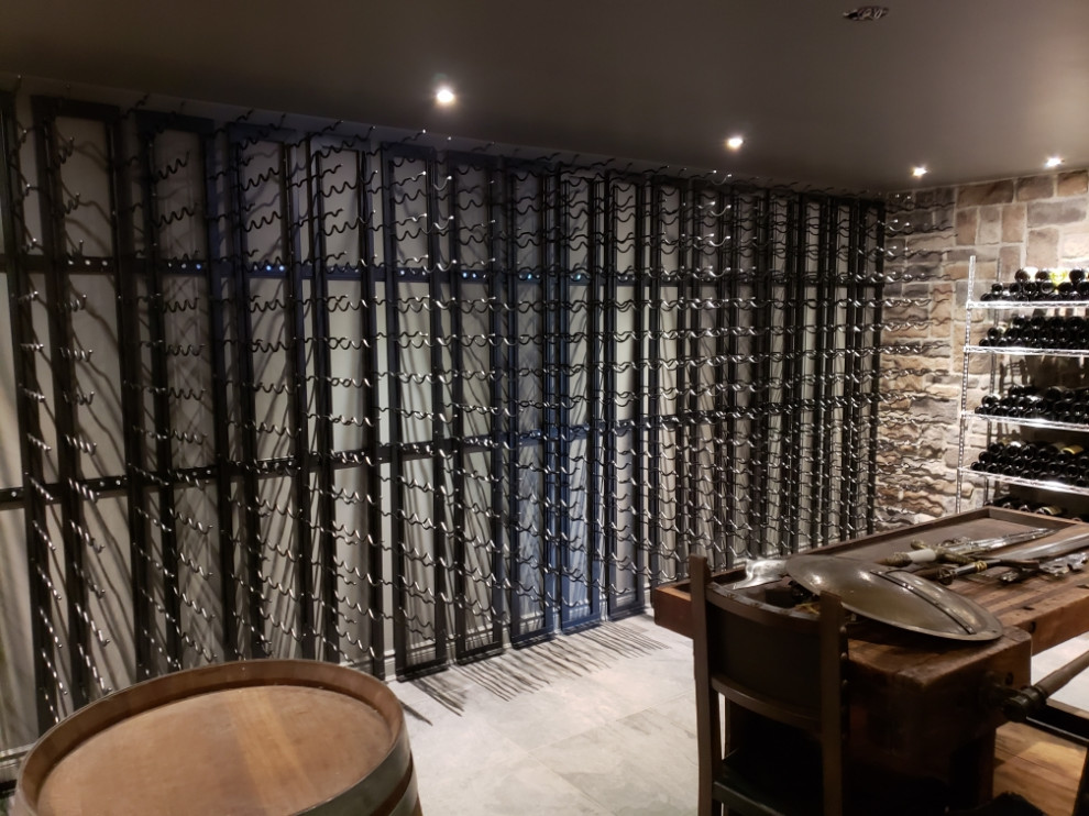 トロントにある広いラスティックスタイルのおしゃれなワインセラー (ディスプレイラック、磁器タイルの床、グレーの床) の写真