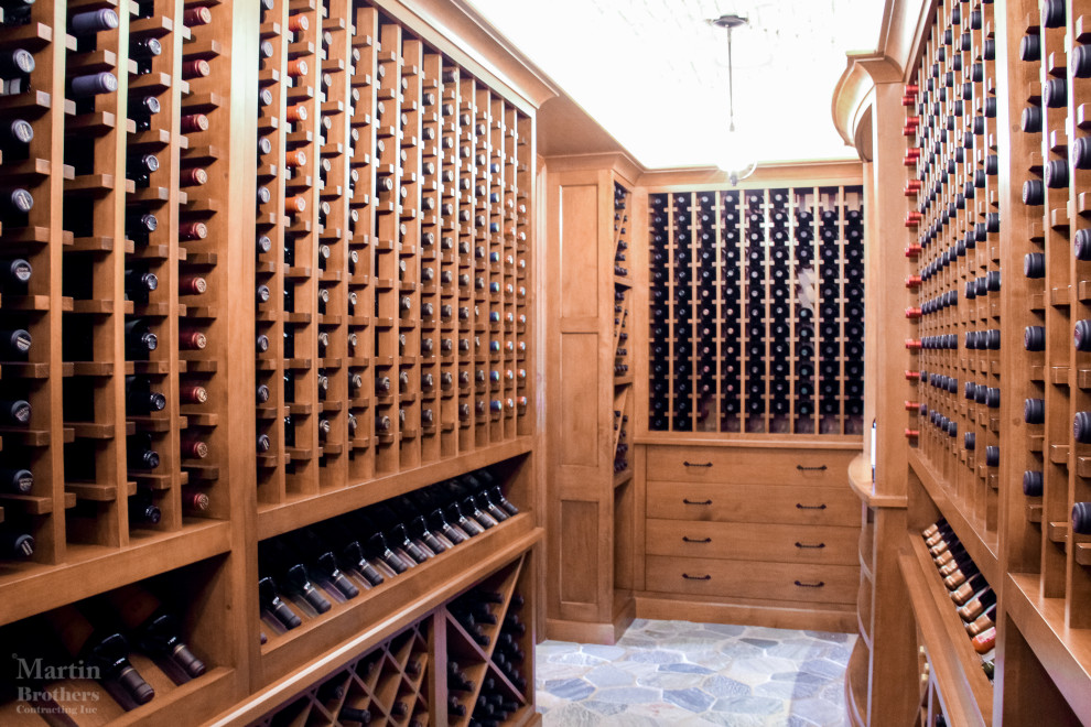 Cette photo montre une grande cave à vin chic avec un sol en ardoise et un présentoir.