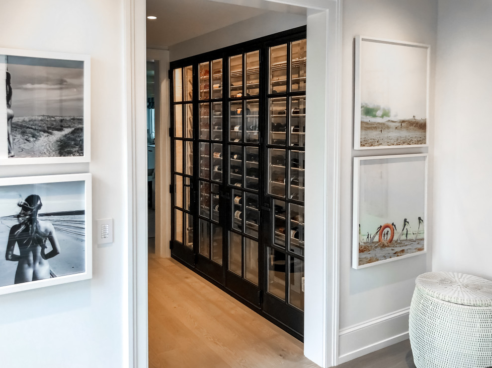 Small trendy light wood floor and beige floor wine cellar photo in Boston with storage racks