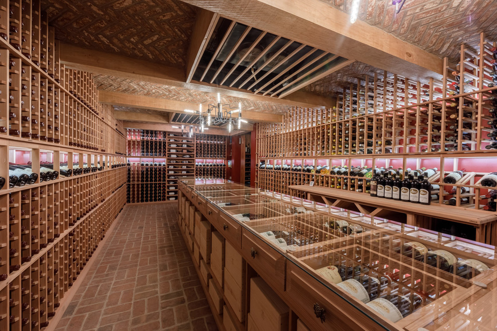 Photo of a large classic wine cellar in Other with brick flooring, storage racks and red floors.