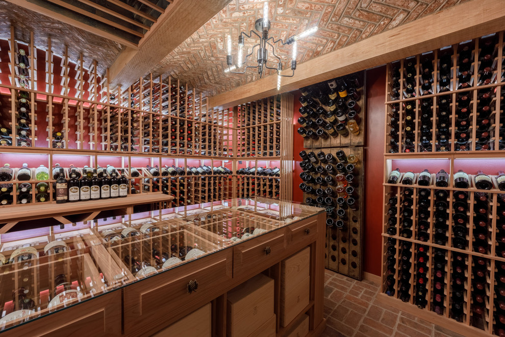 Cette image montre une grande cave à vin traditionnelle avec un sol en brique, des casiers et un sol rouge.