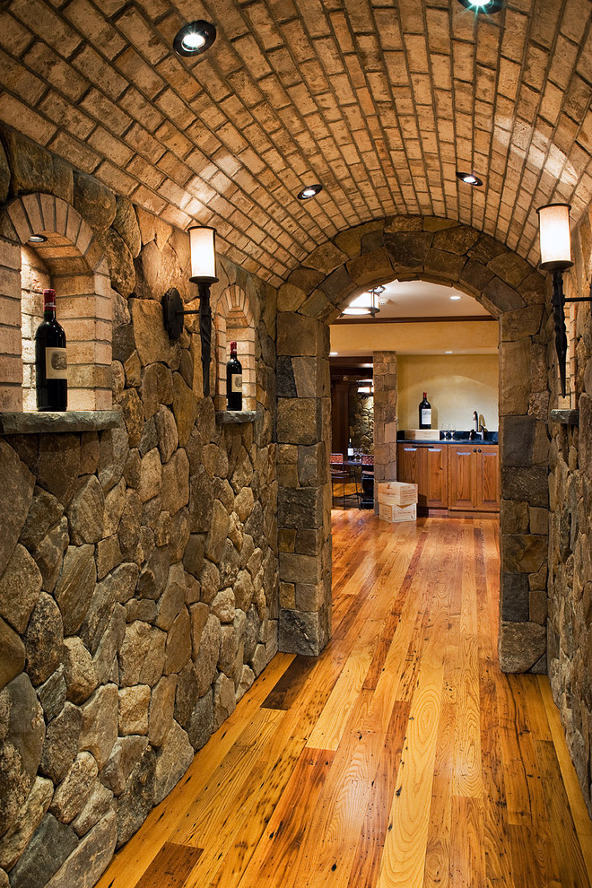 Großer Mediterraner Weinkeller mit diagonaler Lagerung, hellem Holzboden und braunem Boden in Boston
