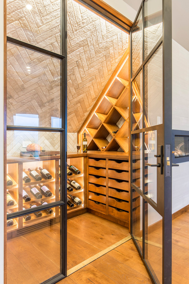 Imagen de bodega contemporánea de tamaño medio con suelo de madera en tonos medios y botelleros de rombos