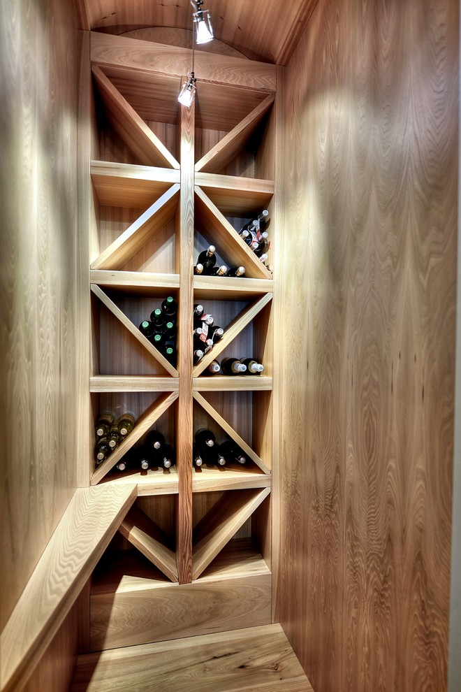 Imagen de bodega contemporánea con botelleros de rombos y suelo de madera en tonos medios