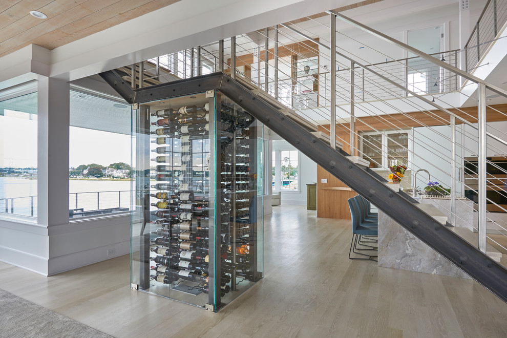 This is an example of a contemporary wine cellar in New York with light hardwood flooring, display racks and beige floors.