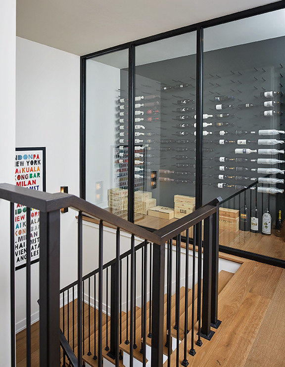 Inspiration for a large contemporary wine cellar in Grand Rapids with light hardwood flooring, storage racks and beige floors.