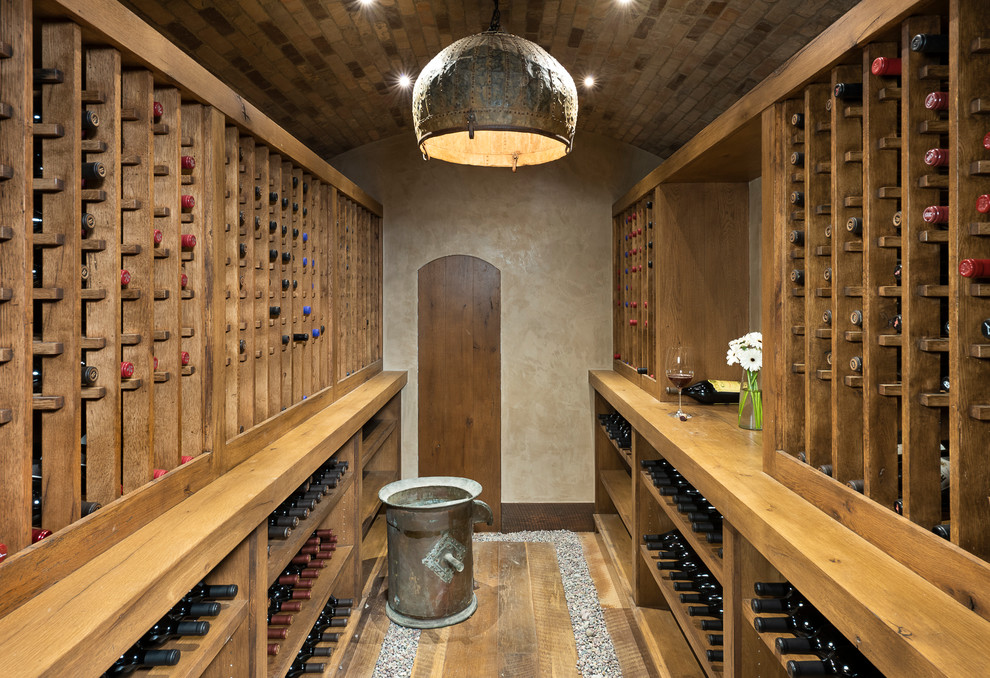 Idée de décoration pour une petite cave à vin chalet avec un sol en bois brun, des casiers et un sol marron.