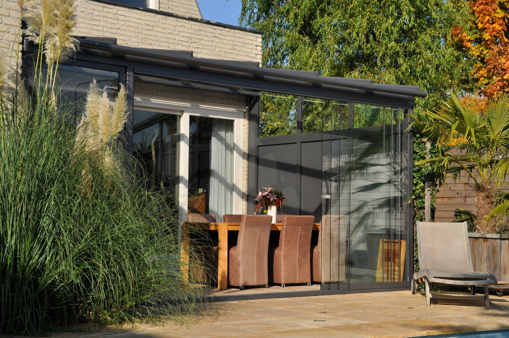 Esempio di una grande veranda contemporanea con pavimento in terracotta, soffitto in vetro e pavimento beige