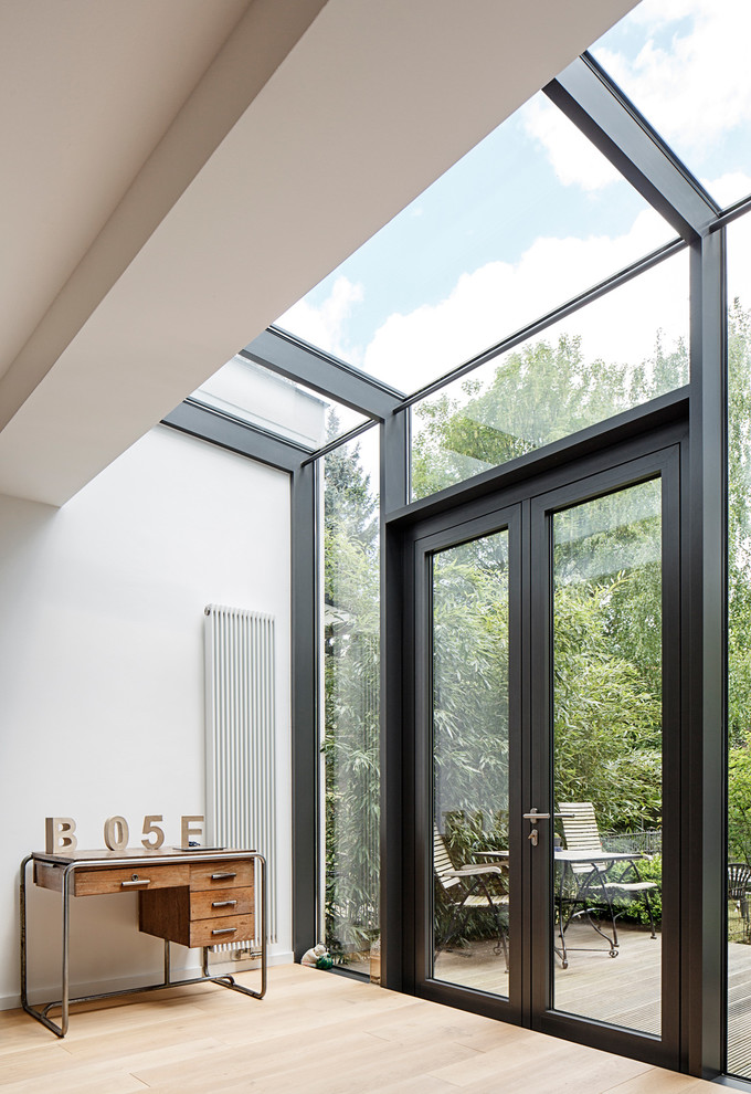 Medium sized contemporary conservatory in Cologne with light hardwood flooring, no fireplace and a skylight.