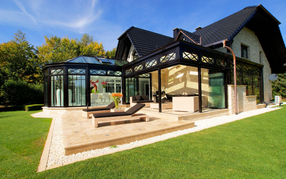 Ispirazione per una grande veranda vittoriana con parquet chiaro, camino classico, lucernario e pavimento marrone