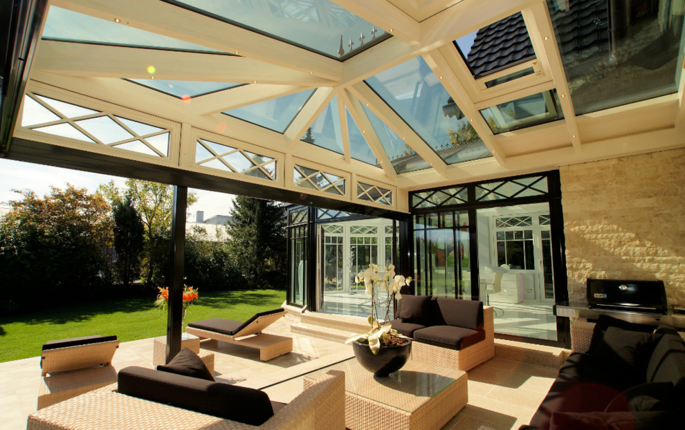 Стильный дизайн: большая терраса в викторианском стиле с стеклянным потолком, полом из известняка, стандартным камином и коричневым полом - последний тренд