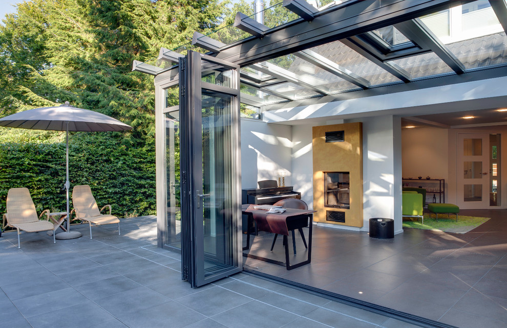 Photo of a medium sized contemporary conservatory in Hamburg with ceramic flooring, a two-sided fireplace, a plastered fireplace surround and a glass ceiling.