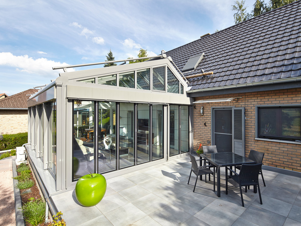 Photo of an expansive contemporary conservatory in Other with porcelain flooring, a glass ceiling and beige floors.