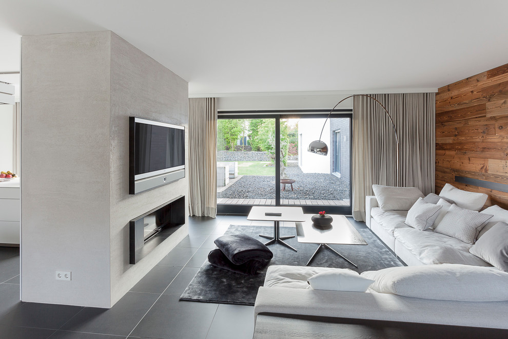 Mittelgroßes, Offenes Modernes Wohnzimmer mit grauer Wandfarbe, Keramikboden, Kamin, verputzter Kaminumrandung und schwarzem Boden in Hannover