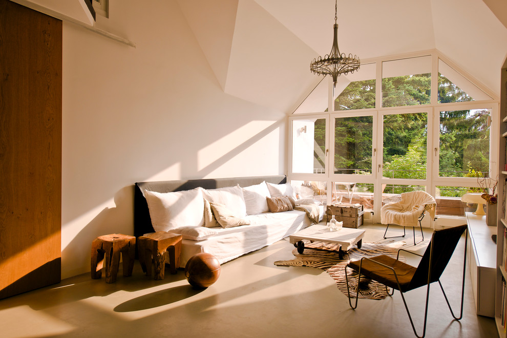 Aménagement d'un grand salon contemporain ouvert avec une salle de réception, un mur blanc et sol en béton ciré.