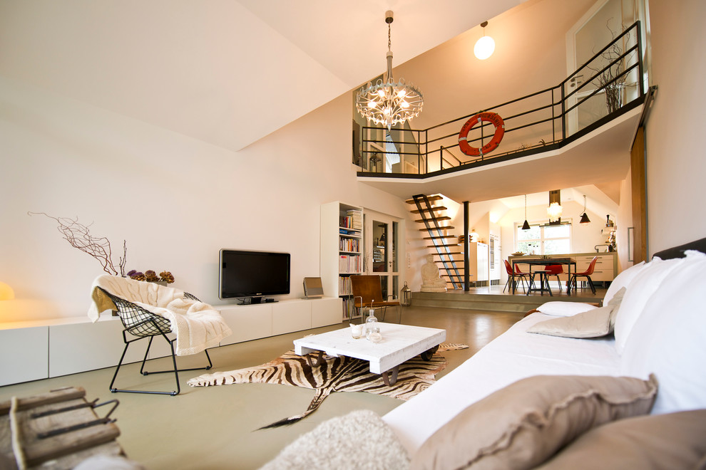 Пример оригинального дизайна: большая открытая, парадная гостиная комната в современном стиле с белыми стенами, бетонным полом и отдельно стоящим телевизором без камина