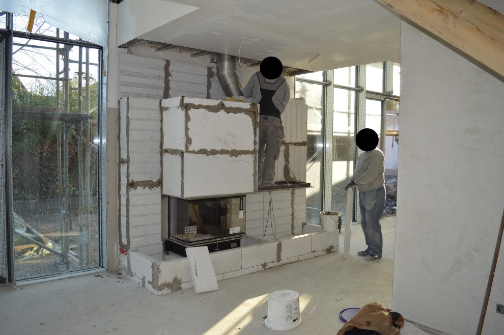 Cette photo montre une grande salle de séjour mansardée ou avec mezzanine tendance avec un mur blanc, parquet clair, une cheminée standard, un manteau de cheminée en plâtre et un sol beige.