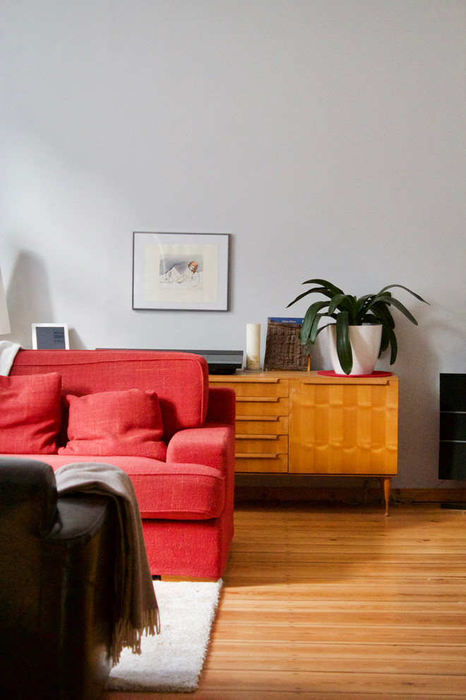 Ejemplo de sala de estar con rincón musical cerrada contemporánea grande con paredes grises, suelo de madera en tonos medios, estufa de leña, marco de chimenea de metal y televisor colgado en la pared