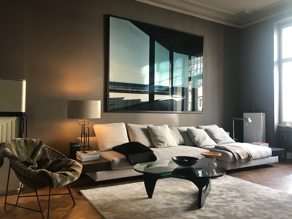 Kleines, Abgetrenntes Modernes Wohnzimmer mit brauner Wandfarbe, Kaminofen, Kaminumrandung aus Metall, braunem Holzboden und braunem Boden in Berlin