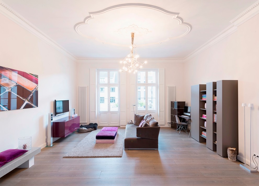 Foto de sala de estar abierta actual grande sin chimenea con paredes blancas, suelo de madera en tonos medios y televisor colgado en la pared