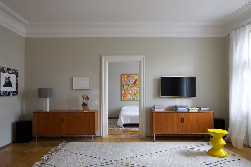 Cette image montre un salon design fermé avec un mur gris, un sol en bois brun, aucune cheminée et un téléviseur fixé au mur.