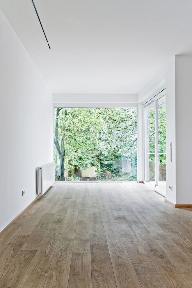 Идея дизайна: гостиная комната в современном стиле с белыми стенами и деревянным полом