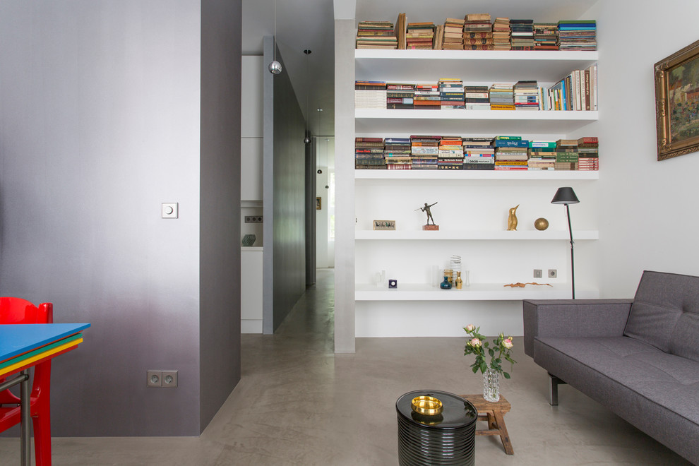 Cette photo montre une petite salle de séjour tendance ouverte avec une bibliothèque ou un coin lecture, aucune cheminée, un mur gris, sol en béton ciré et un sol gris.