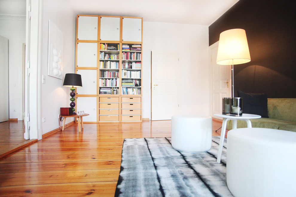 На фото: большая изолированная гостиная комната:: освещение в скандинавском стиле с с книжными шкафами и полками, черными стенами и светлым паркетным полом с