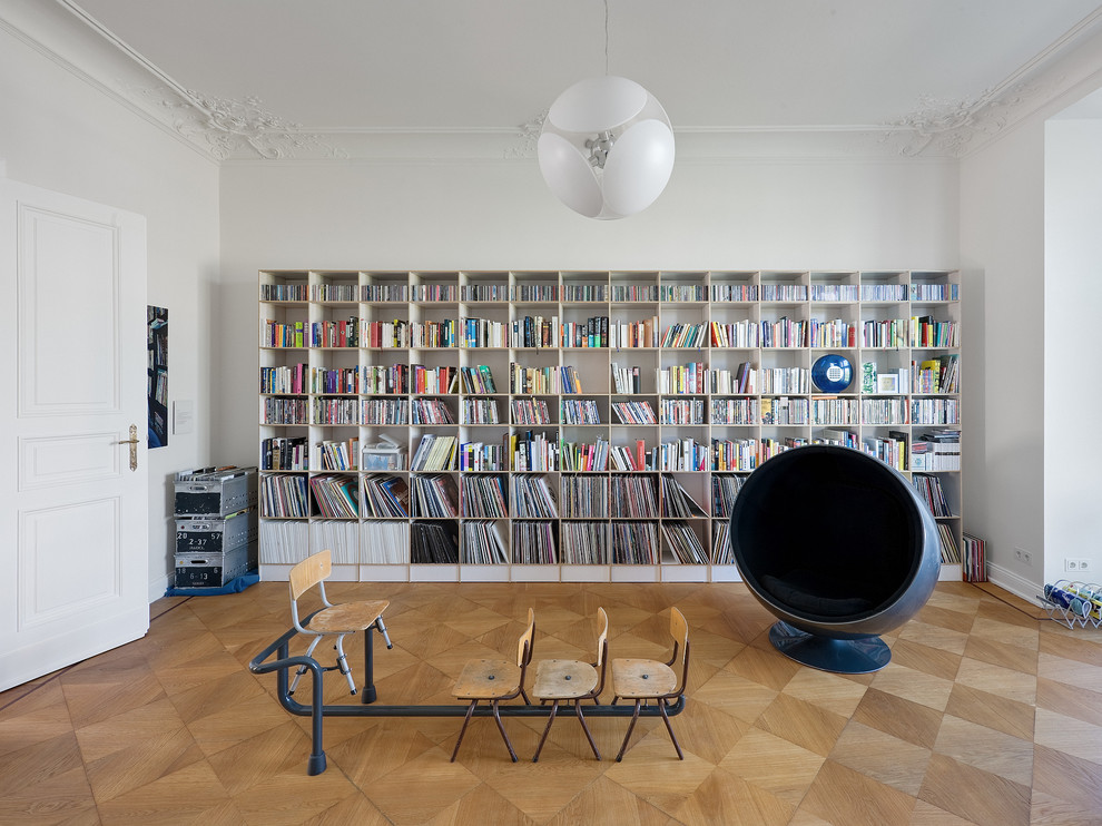 Mittelgroße, Abgetrennte Moderne Bibliothek mit weißer Wandfarbe und braunem Holzboden in Berlin