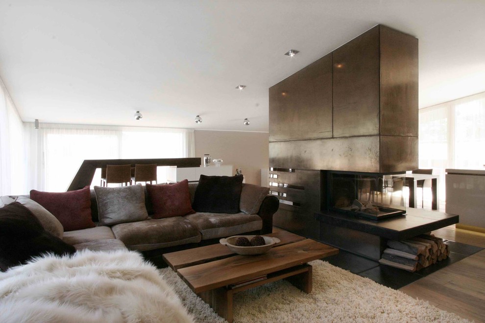 Cette image montre une salle de séjour design avec parquet foncé, une cheminée d'angle et un manteau de cheminée en métal.