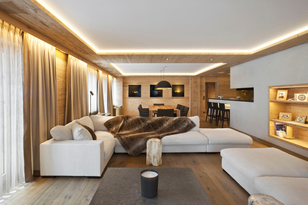 Imagen de sala de estar abierta rústica con paredes blancas, suelo de madera clara y alfombra